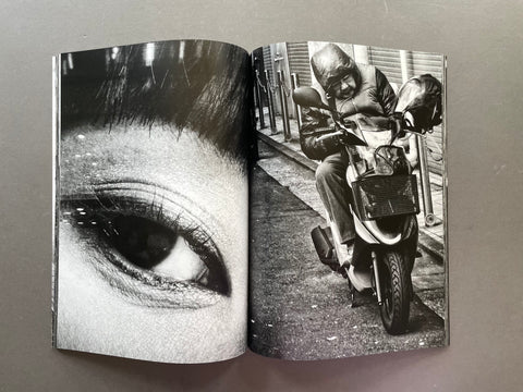 Open book showing a black and white photo of a person riding a scooter and another of an eye.