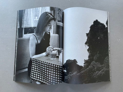 Image of a woman sitting by a table and a tree. 