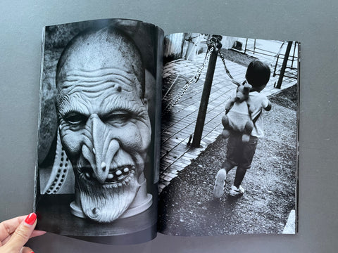 Open book showing black and white photographs, including a detailed close-up of a face and a child with a teddy bear.