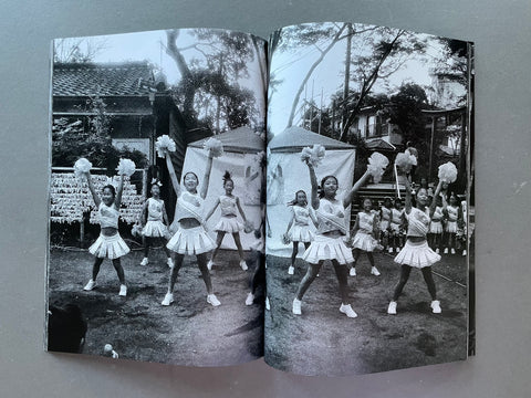 Open book showing black and white photos of a group of girls in uniforms with pom-poms.