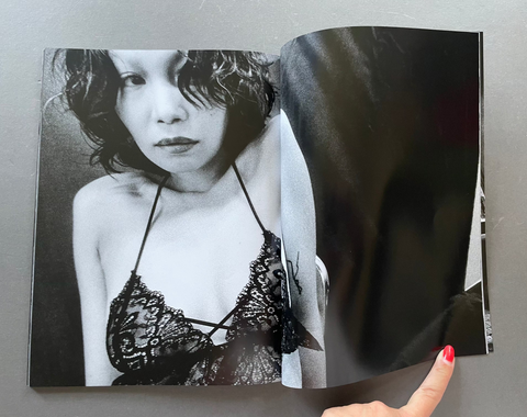 Open book showing a black and white photo of a person in lingerie with a butterfly, held by a hand.