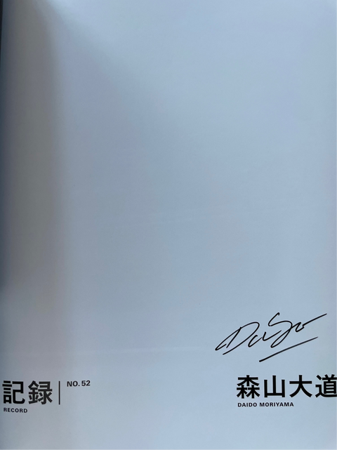 Book cover with text and signature on a light gray background
