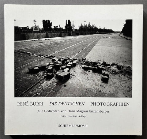 Book titled 'Die Deutschen' by Rene Burri with a white cover featuring a black and white image of a road surface with displaced cobble stones.