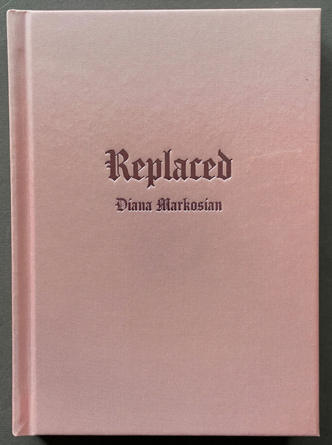 A hardcover book titled 'Replaced' by Diana Markosian, featuring a dusty pink cover with dark gothic lettering, set against a dark gray background.