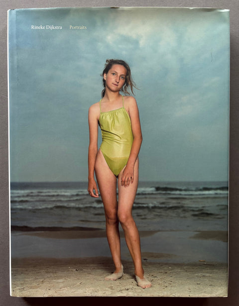 Book titled 'Portraits' by Rineke Dijkstra with a cover featuring a photograph of a young girl standing on a beach wearing a green swimsuit.