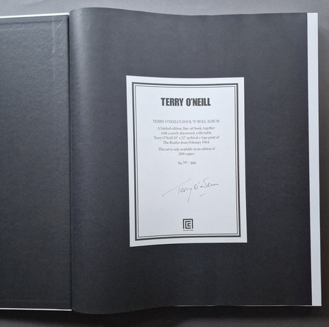 An open book showing a signed interior page with a white label reading 'TERRY O'Neill' and a signature at the bottom, photographed against a dark background.