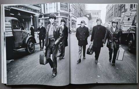 An open book showing a black-and-white printed photograph of four men walking down a city street, photographed from above on a dark surface.