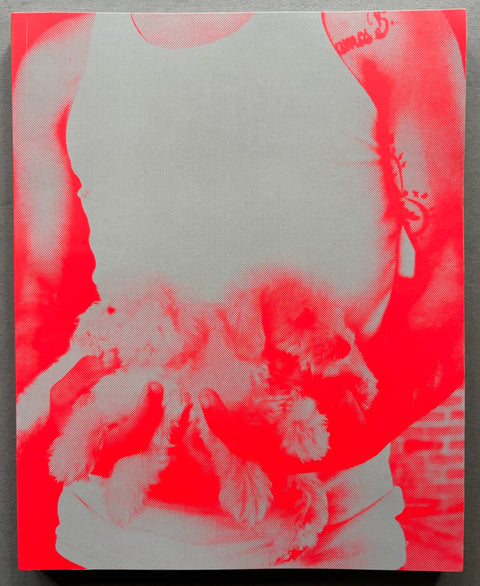 Book titled 'Mi Perro' by Ronald Pizzoferrato with a red and white cover of he image of man holding 2 puppies in his hands.