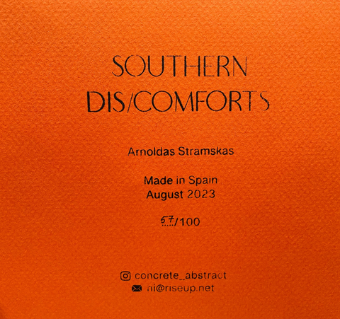 An orange textured paper sheet with black printed text reading 'SOUTHERN DIS/COMFORTS', 'Arnoldas Stramskas', 'Made in Spain', 'August 2023' placed on a gray surface.