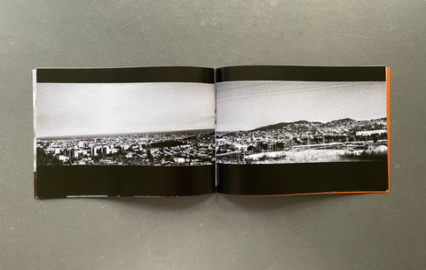 An open book or magazine spread showing a black-and-white panoramic cityscape photograph on the inner pages, photographed from above on a gray textured surface.