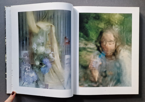 An open art book , showing two printed pages with soft-focus, painterly portraits and floral imagery. 