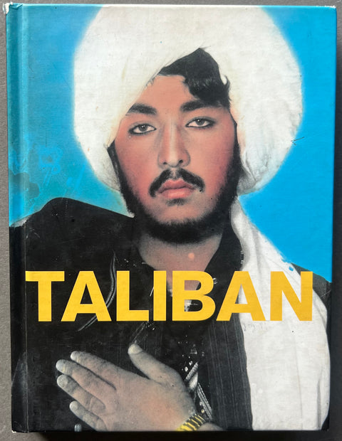 This image features the cover of the first edition of "Taliban" by Thomas Dworzak, a hardback book published in 2002. The cover portrays a striking black and white photograph of a bearded man with a traditional turban, highlighting the book's focus on Taliban soldiers.