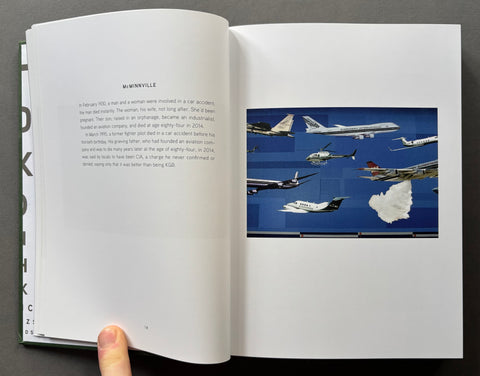 An open book or magazine spread laid on a dark surface, showing printed text on the left page and a color photograph of several airplanes on the right page. A person's finger is visible holding the left page open.