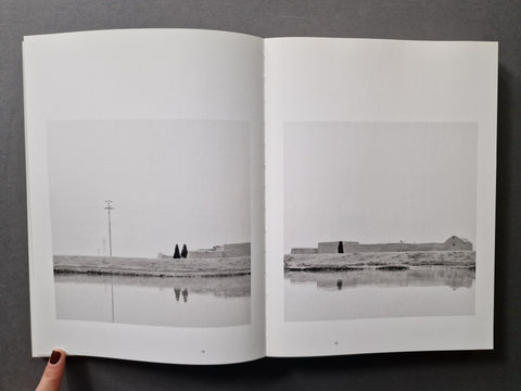 An open book, showing two printed black-and-white landscape photographs on the pages. 