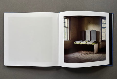 Open book showing a photograph of a room with a bed and window on a gray background