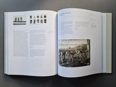 An open book spread showing printed text and black-and-white artwork on white pages, photographed from above on a dark gray surface.