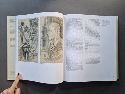 An open art history book displayed flat on a dark gray surface, showing two illustrated pages with sketches and text. A person's finger points to the left page.