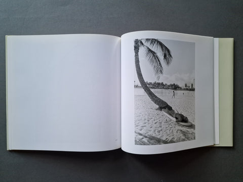 An open hardcover book, showing a black-and-white beach photograph printed on the right page with a blank white left page.
