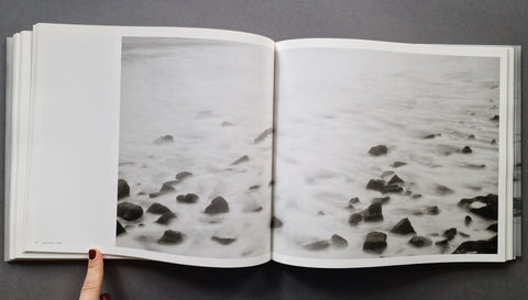 An open book spread showing a seascape with rocks