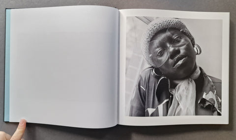 An open book, showing a large blank left page and a black-and-white portrait print 
