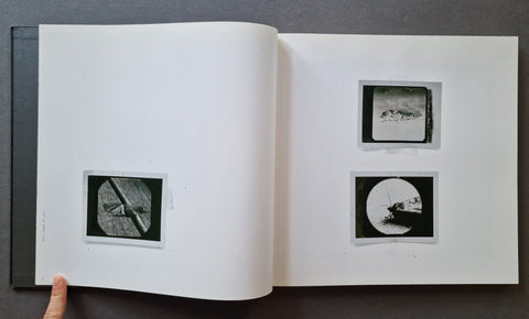 An open book spread on a dark gray surface, showing two black-and-white photographs of moths on the right page and one on the left.
