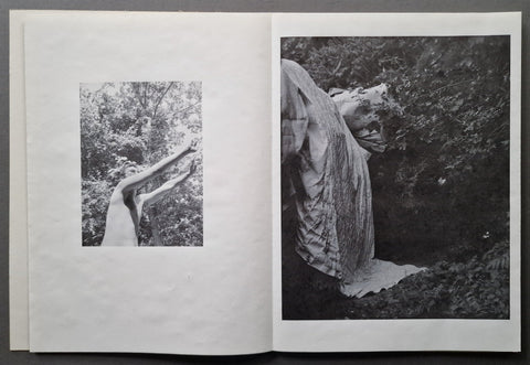 An open book showing two black-and-white photographic panels on white pages, photographed against a dark gray background.