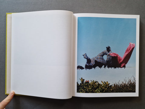 An open book with the left page blank and the right page showing a printed photograph of clothes on a laundry line being blown by the wind