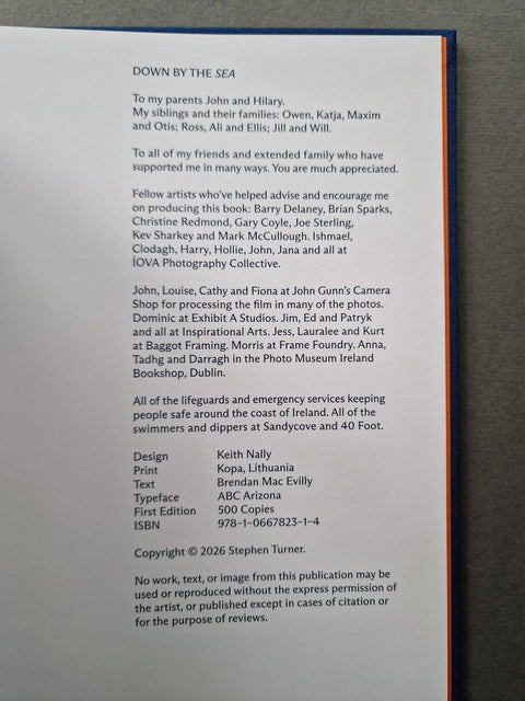 A close-up of a printed book or publication page showing a dedication and publication details, photographed against a dark background with a sliver of orange at the right edge.