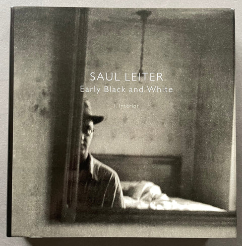 A square book or album cover titled 'SAUL LEITER Early Black and White I Interior' featuring a monochrome photograph of a seated figure in a dim room, photographed against a light neutral background.