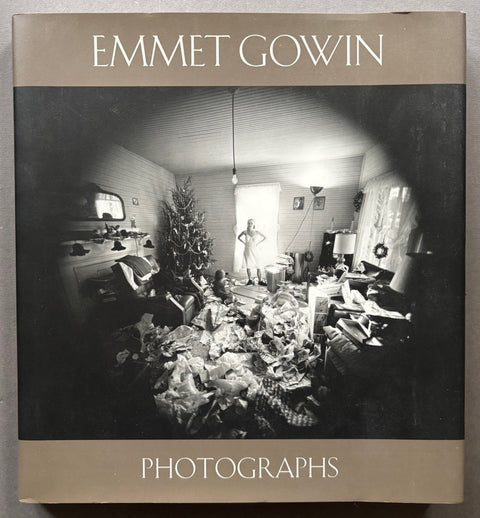 Book titled 'Photographs' by Emmet Gowin with a brown cover featuring the image of a woman in a room with a Christmas tree surrounded by gifts and wrapping paper.