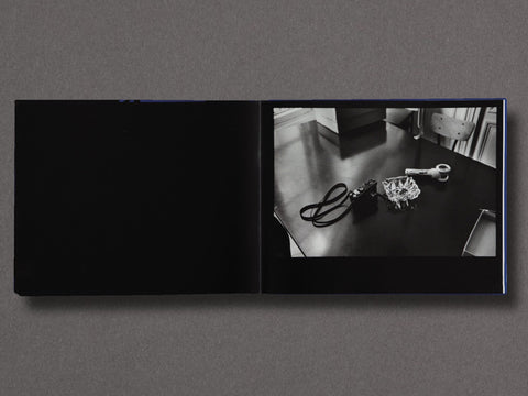 A spread of a book showing a still life photograph of a camera and ashtray on a table