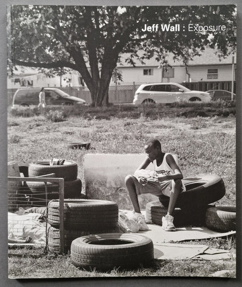 The book cover of Jeff Wall: Exposure with a photo of a black kid sitting on some discarded tyres.