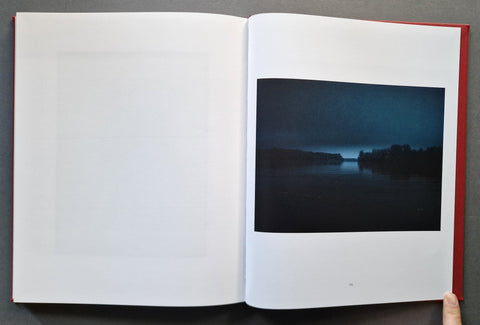 An open book, showing a blank white left page and a printed landscape photograph on the right page.