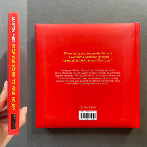 A hardcover book titled 'From Our House to Your House' by Martin Parr, shown with its red back cover and spine held by a hand against a dark gray background.