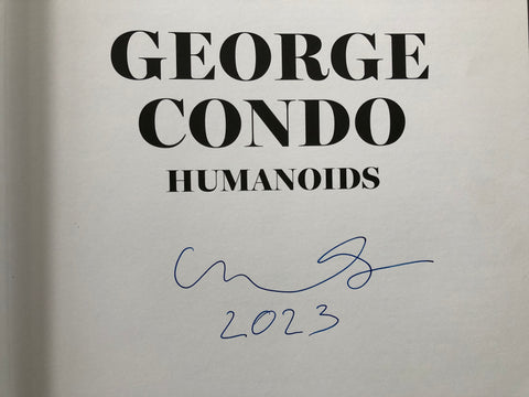 A close-up of a printed page with the title 'GEORGE CONDO HUMANOIDS' in large black serif text on an off-white background, plus a blue handwritten signature and the year '2023' below.