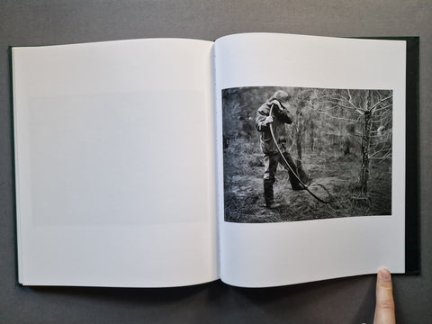 An open book, showing a black-and-white photograph printed on the right page of an otherwise blank white left page. 