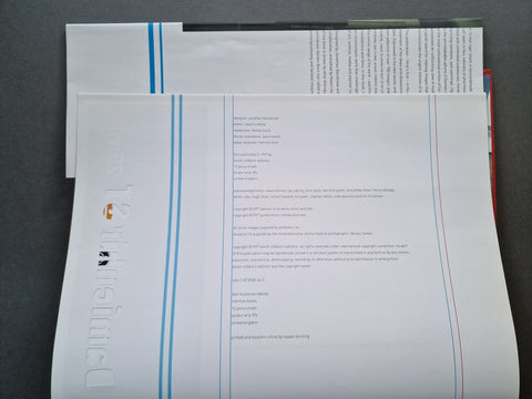 A close-up of printed technical sheets or a booklet with dense text, blue and red vertical lines, and a large vertical wordmark reading 'Tensile.