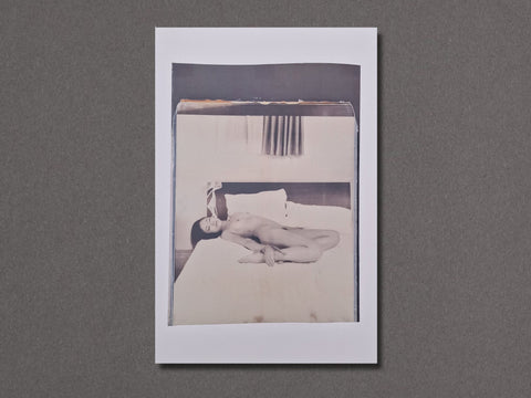 A square photographic art print with a white border, featuring a black and white photograph of a nude woman lying on a bed.
