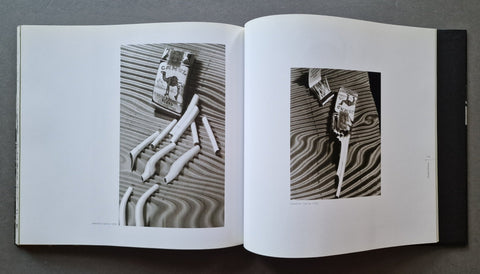 An open book  showing two black-and-white photographic panels of distorted boxes of Camel cigarettes