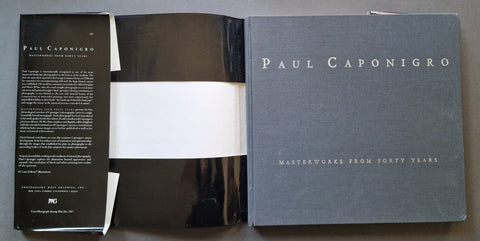 A book cover shown open to reveal the interior, with the right cover in view. The cover is a textured dark gray with the name 'PAUL CAPONIGRO' in white serif text and smaller text reading 'MASTERWORKS FROM FORTY YEARS.