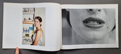 An open book, showing two printed pages. The left page contains a small vertical color photo of a woman standing in front of shelves, and the right page shows a large black-and-white close-up of a woman's mouth and lower face.