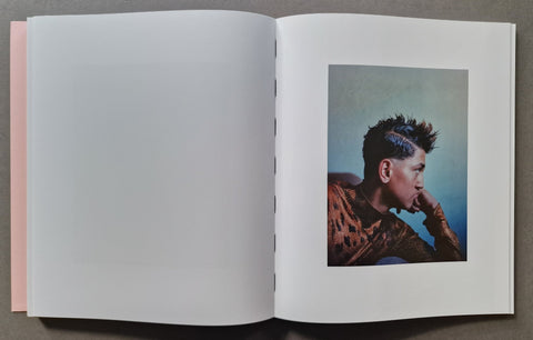An open book, showing a mostly blank white left page and a printed portrait page on the right with a person in profile against a blue background.