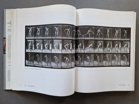An open book spread showing a black-and-white photographic print with multiple sequence frames of a human figure in motion, photographed on a dark gray surface.