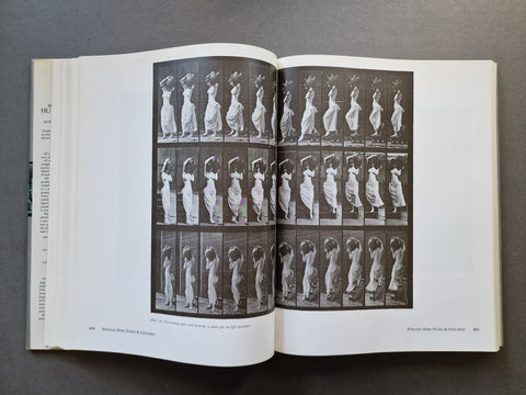 An open vintage book or art print laid flat on a dark gray surface, showing a black-and-white sequence of motion-style photographs printed across both pages.