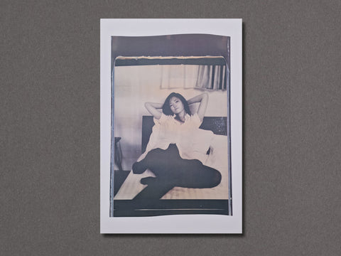 A square photographic art print with a white border, featuring a black and white portrait of a woman sitting on a bed.