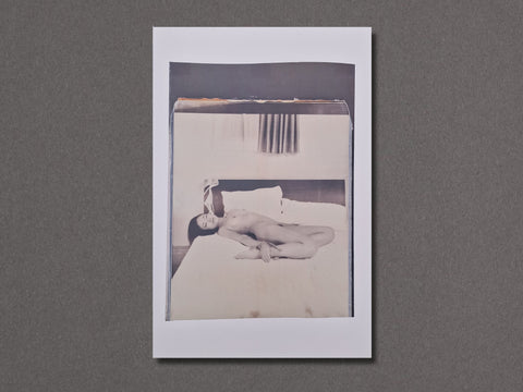 A square photographic art print with a white border, featuring a black and white photograph of a nude woman lying on a bed.