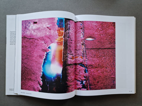 An open book displaying a large, vivid abstract photograph printed across both pages of a puddle and neon lighting
