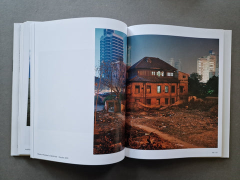 An open book showing a large printed photograph on the right page of an old building at dusk with city buildings in the background.
