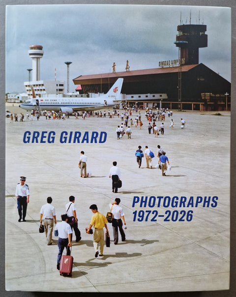 A book cover titled 'GREG GIRARD PHOTOGRAPHS 1972-2026' featuring a vintage airport scene with a passenger airplane, terminal building, and travelers walking on the tarmac.