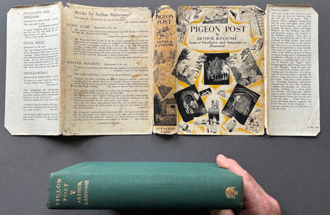 Book titled 'Pigeon Post' by Arthur Ransome with a hand holding a green copy of the book.